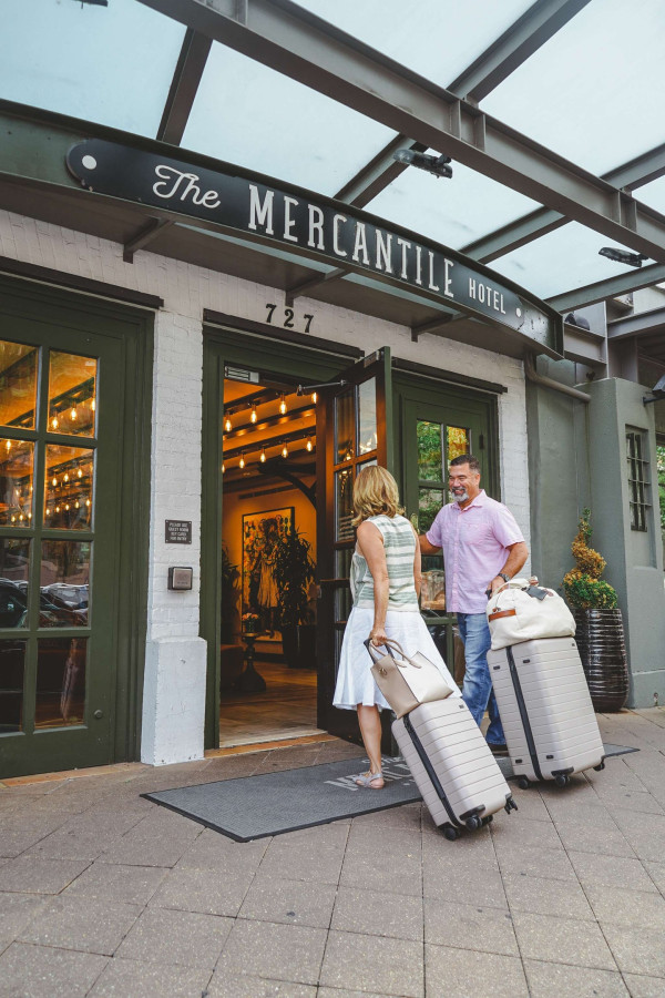 A couple with luggage standing at the entrance of The Mercantile Hotel