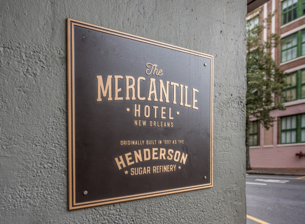 A black plaque with gold lettering on a gray wall